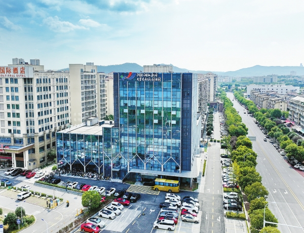 公司外景照片，现代化办公楼，玻璃幕墙设计，周围绿植环绕，阳光明媚
